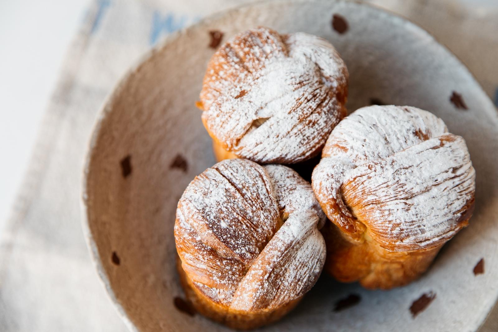 Rhubarb and Custrad Cruffin, Lovingly Artisan, Lake district, Aidan MOnks, Artisan Treats, Summer pastry, Sourdough Bakery, UK top Bakery three of our rhubarb and custard cruffins in a bowl with a delicate dust of icing sugar